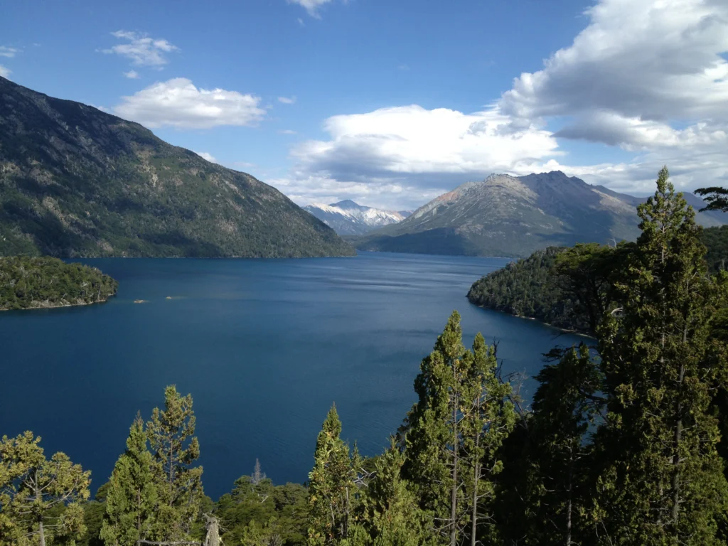 Vista panorámica del Brazo Tristeza desde altura, con el agua azul encajonada entre montañas boscosas.