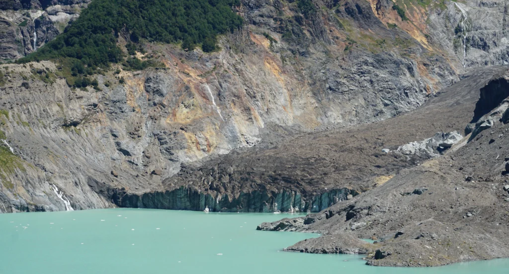 Lengua de sedimento del Ventisquero Negro llegando a la laguna glaciar de agua verdosa.