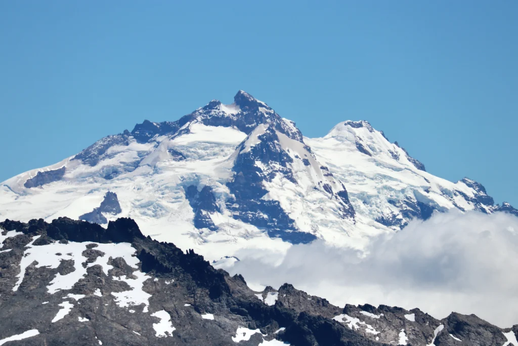 Cumbres nevadas y glaciares del Cerro Tronador sobre un cordón de roca oscura.