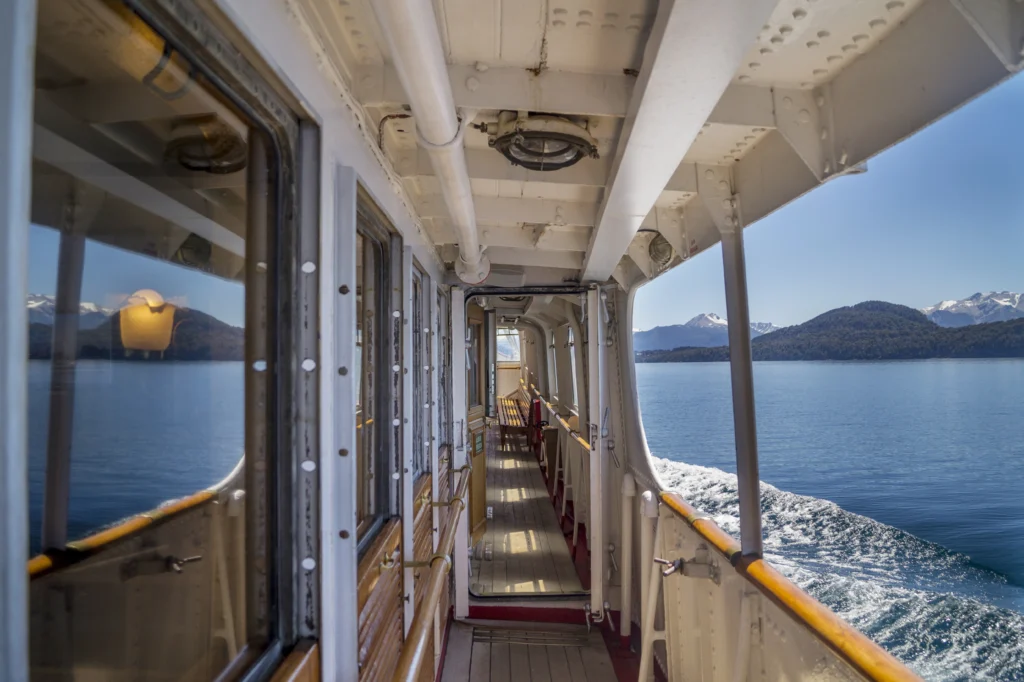 Side deck of the vessel during navigation, with a view of the lake and mountains.