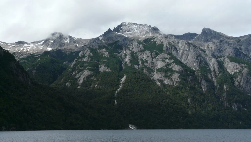 Paredes de roca y cumbres nevadas cayendo sobre el lago, en el cordón del Tronador.