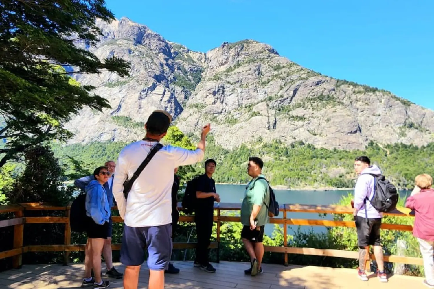 Guía de turismo señalando el cerro López a un grupo desde una pasarela del Circuito Chico en Bariloche.