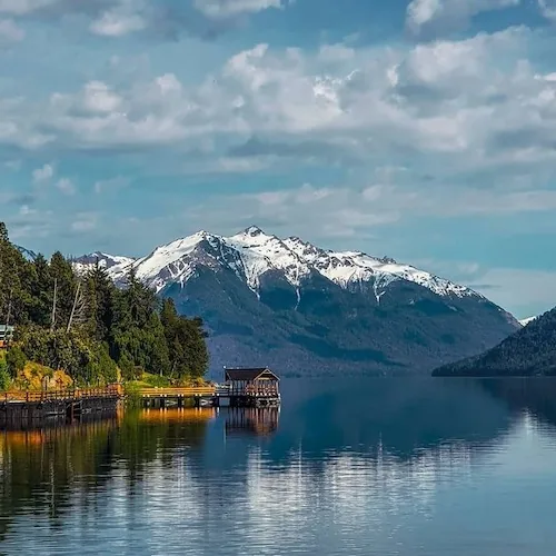 Lago Traful con cerros nevados y muelle de madera en el Circuito Grande